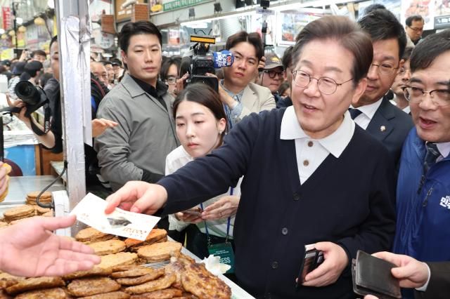 더불어민주당 이재명 대선 후보가 골목골목 경청투어 단양8경편에 나선 4일 충북 단양군 단양구경시장에서 떡갈비를 사먹으면서 지역화폐를 사용하고 있다 사진연합뉴스