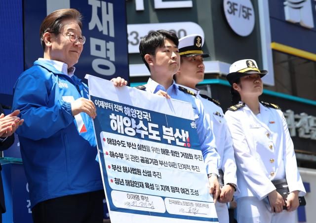 부산연합뉴스 황광모 기자 더불어민주당 이재명 대선 후보가 14일 부산 부산진구 서면 젊음의 거리에서 열린 유세에서 권기흥 에이치라인해운해상직원노조 위원장과 해양수도 부산 협약서에 서명한 후 기념 촬영하고 있다 사진연합뉴스