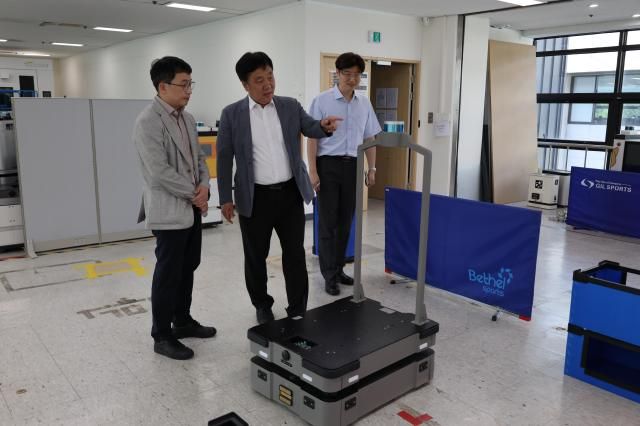 김영신 기정원장가운데이 천영석 대표이사왼쪽와 함께 물류 로봇 시스템을 확인하고 있다 사진기정원