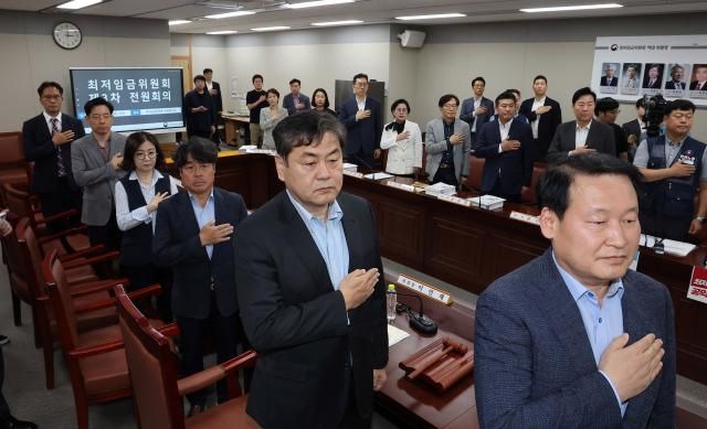 최저임금위원회 위원들이 정부세종청사에서 열린 최저임금위원회 제3차 전원회의에서 국기에 경례하고 있다 사진연합뉴스