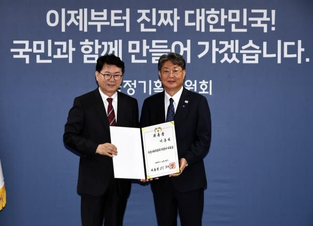 이한주 국정기획위원회 위원장왼쪽이 16일 서울 종로구 정부서울청사 창성동 별관에서 열린 출범식에서 경제2분과장을 맡은 더불어민주당 이춘석 의원에게 위촉장을 수여한 뒤 기념촬영을 하고 있다 사진연합뉴스