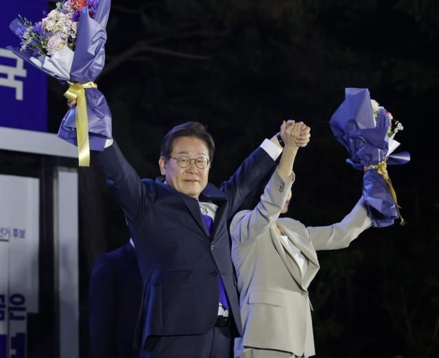 제21대 대통령 당선이 확실시되는 이재명 더불어민주당 대선 후보와 부인 김혜경 여사가 4일 서울 여의도 국회 인근에서 당 주최로 열린 국민개표방송 행사에 참석해 꽃다발을 받고서 시민들을 향해 두 팔을 들어 인사하고 있다 사진연합뉴스