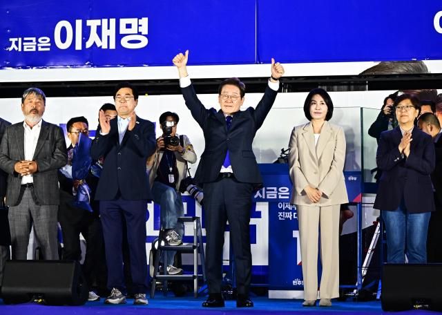 제21대 대통령 당선이 확실시되는 이재명 더불어민주당 대선 후보와 부인 김혜경 여사가 4일 서울 여의도 국회 인근에서 당 주최로 열린 국민개표방송 행사에 참석해 시민들을 향해 인사하고 있다 사진연합뉴스