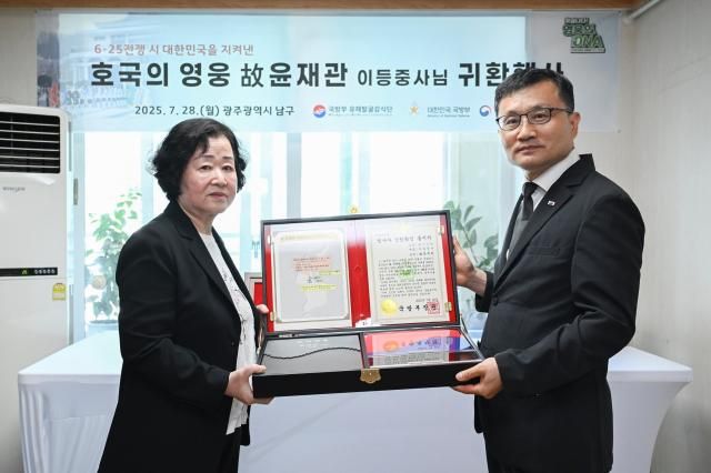 고 윤재관 이등중사현 병장의 유가족딸 윤금순 씨왼쪽·74세에게 호굴의 얼 함를 전달하는 이근원 국방부유해발굴감식단장오른쪽 사진국방부