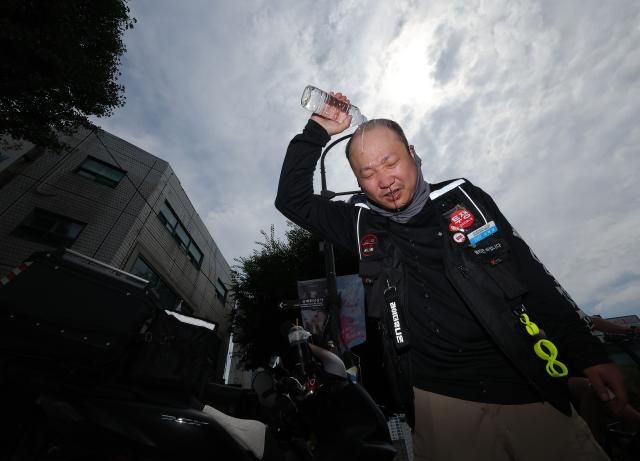 폭염이 계속되는 서울 시내에서 한 배달 노동자가 물을 뿌리며 더위를 식히고 있다 사진연합뉴스