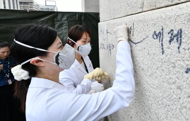 국립고궁박물관 유물과학과 관계자들이 11일 서울 경복궁 광화문 석축 낙서를 제거하고 있다 사진연합뉴스 