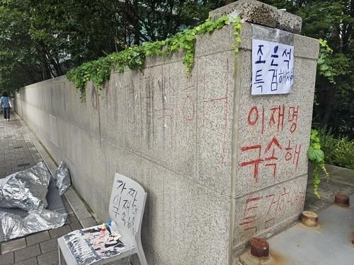 윤석열 전 대통령 부부 사저인 서초동 아크로비스타 담벼락에 한 여성이 낙서한 모습 사진연합뉴스