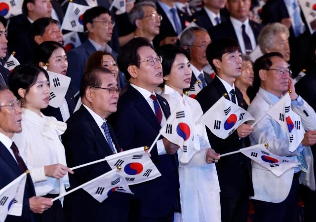 이재명 대통령과 김혜경 여사가 15일 서울 세종문화회관에서 열린 80주년 광복절 경축식에서 참석자들과 함께 태극기를 흔들며 광복절 노래를 제창하고 있다사진연합뉴스