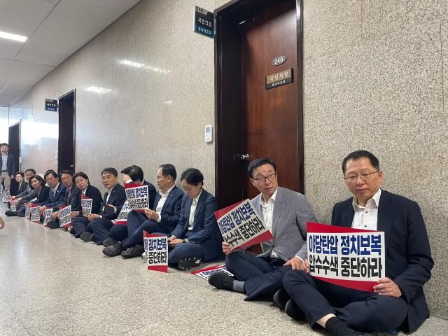 국민의힘 소속 의원들이 3일 국민의힘 원내대표실 앞에 특검 압수수색을 기다리며 피켓을 들고 앉아 있다 사진이다희 기자