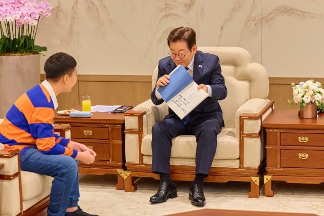 이재명 대통령이 4일 서울 용산 대통령실 청사에서 열린 어린이 초청 행사에 참석한 어린이에게 책을 선물하고 있다 사진대통령실