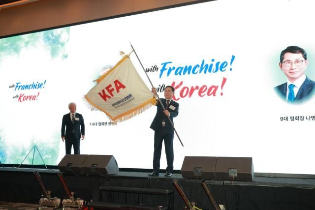 19일 콘래드 서울 그랜드볼룸에서 열린 '협회장 이·취임식 및 비전 선포식'에서 나명석 제9대 한국프랜차이즈산업협회 회장이 정현식 제8대 회장에게 협회기를 이양받고 포즈를 취하고 있다. [사진=유대길 기자 dbeorlf123@ajunews.com]
