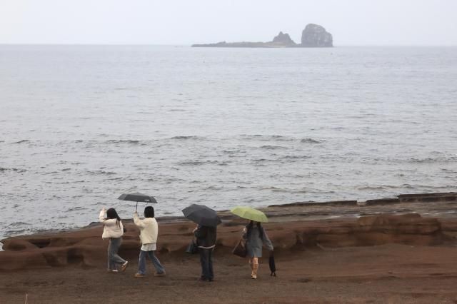 10일 오전 제주 서귀포시 안덕면 사계리 해안을 찾은 관광객이 우산을 들고 바닷가 정취를 즐기고 있다 사진연합뉴스