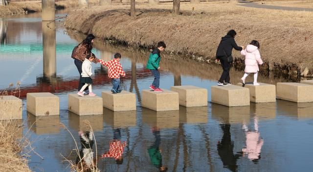 포근한 봄 날씨를 보인 25일 인천 연수구 승기천에서 어린이들이 징검다리를 건너고 있다 사진연합뉴스