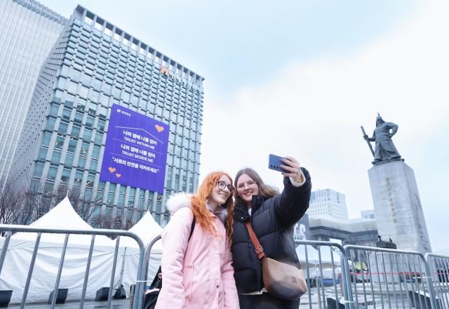 18일 서울시 종로구 현대해상 본사 외벽의 방탄소년단의 노래 가사를 인용한 신뢰와 안전 메시지를 배경으로 외국인 방문객들이 사진을 촬영하고 있다 사진현대해상 