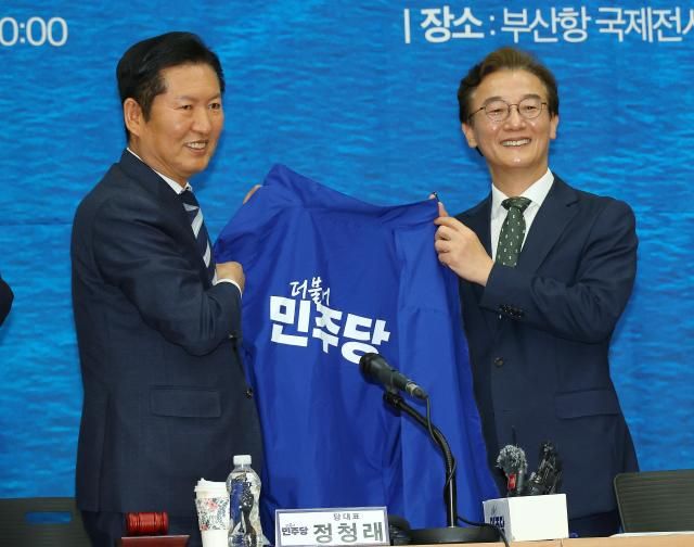 정청래 더불어민주당 대표가 15일 오전 부산 동구 부산항국제전시컨벤션센터에서 열린 부산 현장 최고위원회에서 전재수 부산시장 후보에게 파란 점퍼를 입혀주기 전 들어 보이고 있다 사진연합뉴스