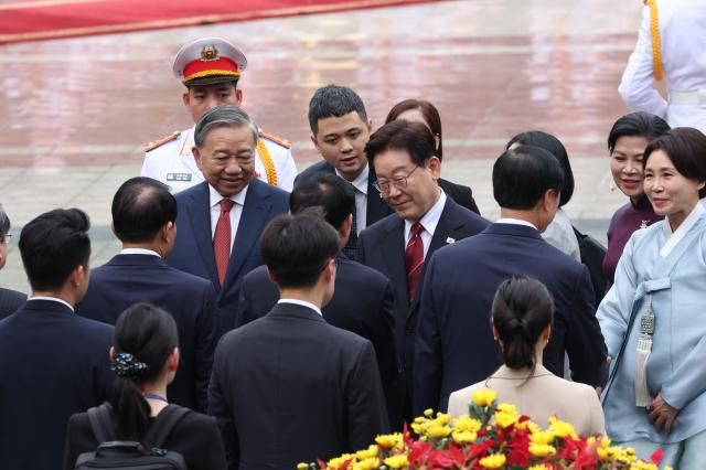 베트남을 국빈 방문한 이재명 대통령이 22일현지시간 하노이 주석궁에서 열린 공식환영식에서 또 럼 공산당 서기장 겸 국가주석의 안내를 받으며 수행원들과 인사하고 있다 사진연합뉴스