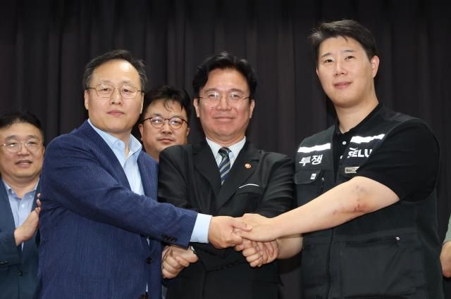 지난 20일 경기도 수원시 장안구 경기고용노동청에서 열린 삼성전자 임금협상을 마친 후 여명구 삼성전자 DS 피플팀장과 최승호 삼성그룹 초기업노동조합 삼성전자지부 위원장이 잠정 합의안에 서명한 후 김영환 고용노동부 장관과 손을 맞잡고 있다 사진연합뉴스