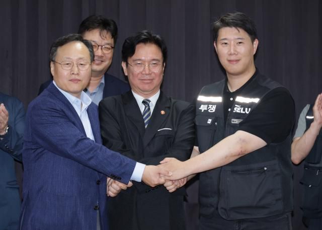지난 20일 경기도 수원시 장안구 경기고용노동청에서 열린 삼성전자 임금협상을 마친 후 여명구 삼성전자 DS디바이스솔루션·반도체 사업 담당 피플팀장과 최승호 삼성그룹 초기업노동조합 삼성전자지부 위원장이 잠정 합의안에 서명한 후 김영환 고용노동부 장관과 손을 맞잡고 있다 사진연합뉴스
