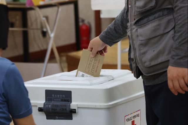 제9회 전국동시지방선거 사전투표 이틀차인 30일 오전 광주 광산구 우산동행정복지센터 3층에 마련된 사전투표소에서 한 유권자가 투표함에 용지가 담긴 봉투를 넣고 있다 사진연합뉴스