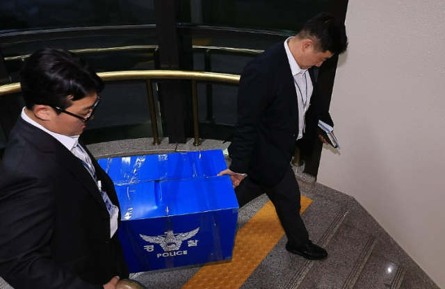 6·3 전국동시지방선거 투표용지 부족 사태를 들여다보고 있는 검경 합동수사본부 관계자들이 지난 11일 경기도 과천 중앙선거관리위원회에서 압수수색을 마친 뒤 압수품을 들고 건물을 나서고 있다 사진연합뉴스
