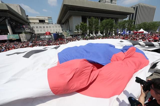 2026 북중미 월드컵 조별리그 A조 한국과 체코의 경기가 열린 12일 종로구 광화문광장에서 시민들이 응원전을 펼치며 애국가 연주 때 대형 태극기를 펼치고 있다 사진연합뉴스