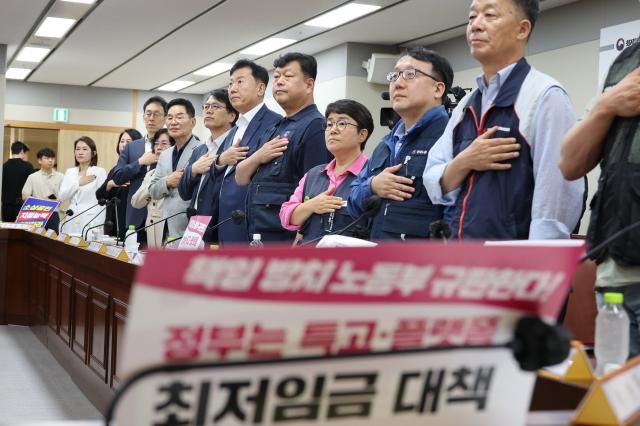 18일 정부세종청사 최저임금위원회에서 열린 제7차 전원회의에서 근로자·사용자·공익 위원들이 국기에 경례하고 있다 사진연합뉴스