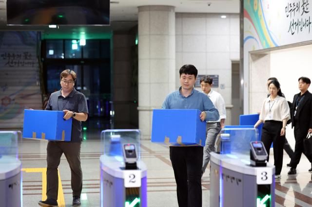지난 23일 압수수색을 마친 합동수사본부 관계자들이 과천 중앙선거관리위원회에서 나오고 있다 투표용지 부족 사태 진상 규명을 위한 검경 합동수사본부는 이날 오전부터 경기도 과천시 중앙선관위와 송파구·강남구·서초구 선관위 등을 압수수색했다 사진연합뉴스