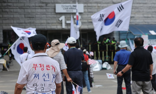 6·3 지방선거 투표용지 부족 사태로 인한 개표소 봉쇄 시위가 계속되고 있는 지난 5일 서울 송파구 올림픽공원 핸드볼경기장 출입문 앞에서 참가자들이 구호를 외치고 있다 사진연합뉴스