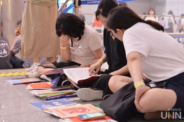 2025 수시박람회가 열린 코엑스에서 학부모와 수험생이 대학 책자를 보며 이야기를 나누고 있다. (사진=한국대학신문DB)