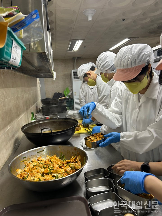 학생들이 조리한 음식을 도시락에 담고 있다.