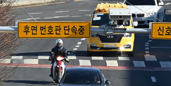 경기도 수원시 한 도로에 설치된 후면 무인교통 단속 카메라 앞을 오토바이 운전자가 지나가고 있다. 뉴시스