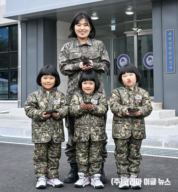 해군 제8전투훈련단 소속 이은주 상사와 세쌍둥이 딸(왼쪽부터 장은진(첫째), 장소진(셋째), 장유진(둘째) 양, 5세)들이 지난달 26일 8전단 예하 예비전력관리전대 건물 앞에서 소아암 아동 돕기를 위해 자른 각 25cm 길이의 머리카락을 손에 들고 기념사진을 촬영하고 있다.&nbsp; (사진=해군)