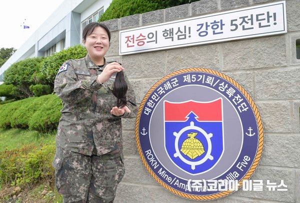 해군 5전단 인사참모실 소속 심규진 대위가 6월9일 5전단 표지석 앞에서 30cm 모발을 들고 기념사진을 촬영하고 있다. (사진=해군)