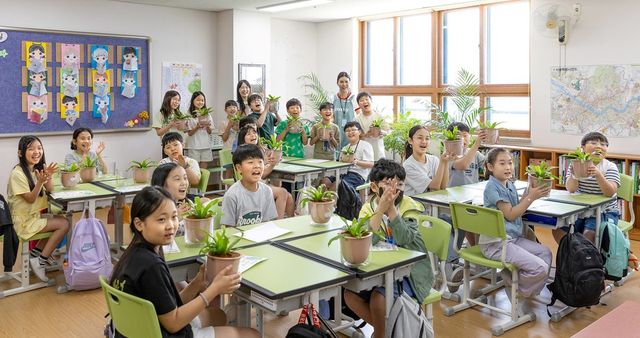 코웨이 임직원 봉사자들과 초등학생들이 '청정학교 교실숲 제7호' 조성을 기념해 단체 사진을 찍고 있다. (사진=코웨이 제공)