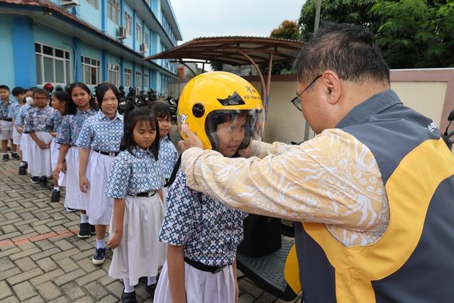 KB손해보험 곽종득 인도네시아 법인장이 현지 학생들에게 안전모를 씌워주고 있다. [사진=KB손해보험]
