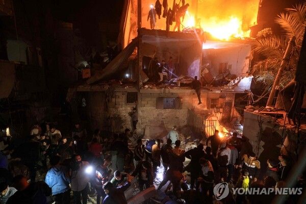 불타는 이스라엘 공습 현장에 모인 가자 주민들 [사진=AFP=연합뉴스]