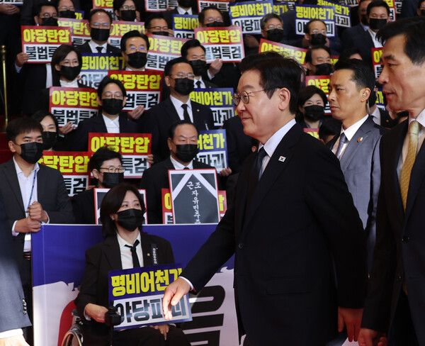 이재명&nbsp;대통령이 4일 내년도 정부 예산안에 대한 시정연설을 하기 위해 서울 여의도 국회에 도착해 침묵시위를 하는 국민의힘 의원들 앞을 지나고 있다.&nbsp;국민의힘 의원들은 추경호 전 원내대표에 대한 내란특검팀의 영장청구를 규탄하는 피켓을 들고서 침묵시위를 했다. [사진=연합뉴스]