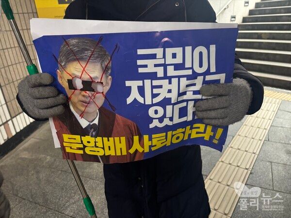 윤석열 대통령의 지지자들이 문형배 헌법재판소장 권한대행의 사진에 눈알이 뚫려 있는 사진과 함께 ‘국민이 지켜보고 있다, 문형배 사퇴하라’라고 적힌 손피켓을 들고 있다. [사진=안다인 기자]