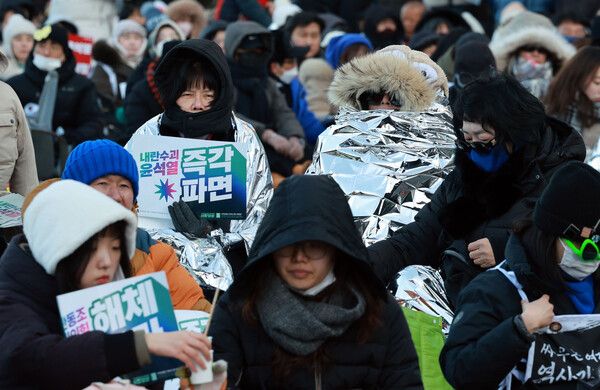강추위가 계속된 8일 서울 종로구 경복궁역 일대에서 열린 윤석열 대통령 즉각 퇴진 사회대개혁 비상행동 주최 10차 범시민대행진 집회에서 참가자들이 집회를 지켜보고 있다. [사진=연합뉴스]