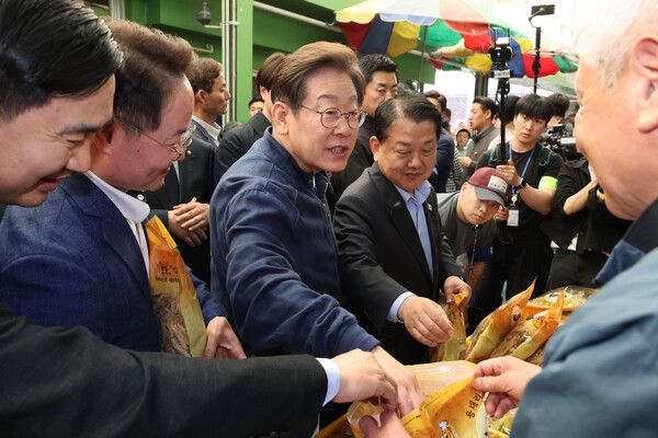 더불어민주당&nbsp;이재명&nbsp;대선 후보가 '골목골목 경청투어' 접경지역 방문 이틀째인 2일 강원도 인제군 원통전통시장에서 건어물 가게에 들러 황태채를 맛보며 상인과 대화하고 있다. [사진=연합뉴스]