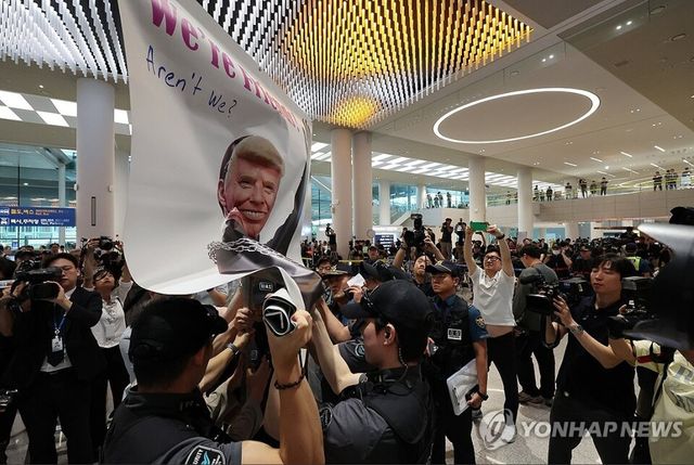 미국 이민당국에 의해 조지아주에 구금됐던 한국인 근로자들이 귀국한 12일 오후 3시20분경 인천국제공항 제2여객터미널 입국장에서 시민단체 활빈당이 미 트럼프 대통령과 미 이민단속국을 풍자한 플랭카드를 들고 시위를 벌였다.&nbsp;공항경찰대가 시민단체의 시위를 저지하고 있다. 2025.9.12 [사진=연합뉴스]