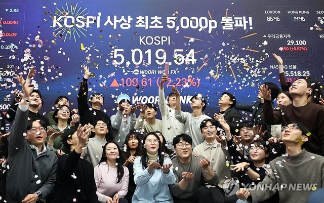 코스피 지수가 장중 사상 처음으로 5,019.54를 기록한 22일 서울 중구 우리은행 본점 딜링룸에서 딜러들이 코스피 지수 5,000선 돌파를 축하하고 있다. 2026.1.22 [사진=연합뉴스]