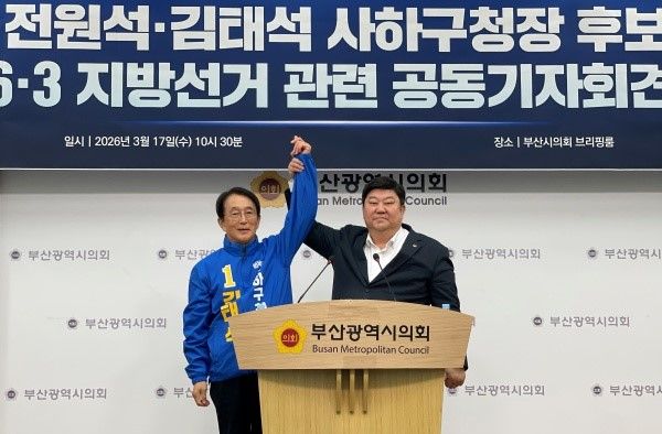 민주당 부산 사하구청장 공천 경쟁을 벌이던 전원석(오른쪽) 시의원이 17일 시의회에서 단일후보로 합의한 김태석 전 구청장의 손을 들어올리고 있다.[사진=정하룡 기자]