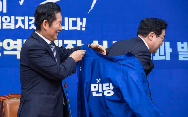 더불어민주당 정청래 대표(왼쪽)가 인천시장 후보로 결정된 박찬대 의원에게 4일 국회에서 열린 중앙당 공천관리위원회 지방선거 후보 공천 심사 결과 발표 회견에서 당의 후보를 상징하는 파란 점퍼를 입혀주고 있다. 2026.3.4. [사진=연합뉴스]