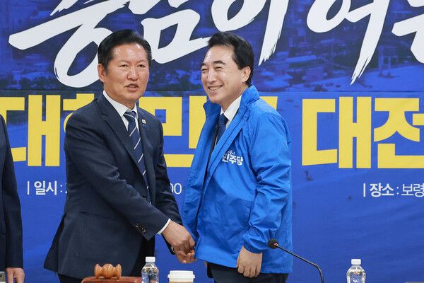 &nbsp;더불어민주당 정청래 대표가 20일 충남 보령머드테마파크에서 열린 현장 최고위원회의에 참석해&nbsp;박수현&nbsp;충남도지사 후보에게 당 점퍼를 입혀주고 있다. [사진=연합뉴스]