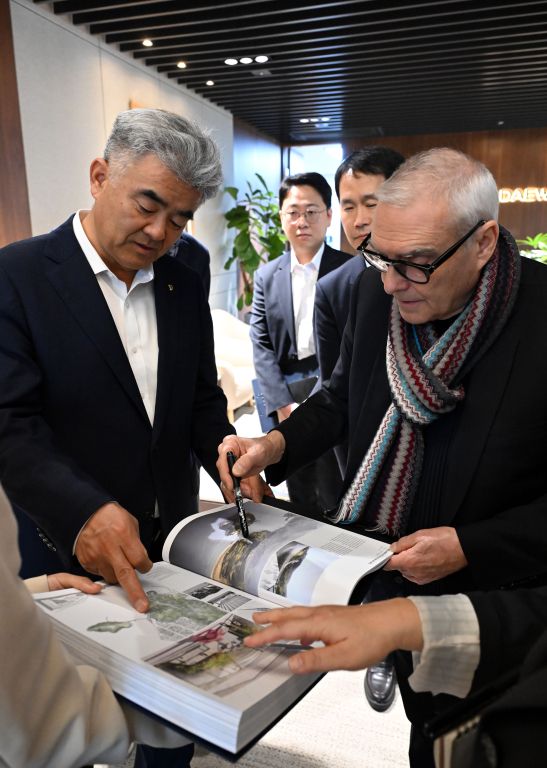 도미니크 페로(오른쪽)가 본인의 작품집 중 여수 장도 설계에 대해 정원주 회장에게 설명하고 있다.[사진=대우건설]