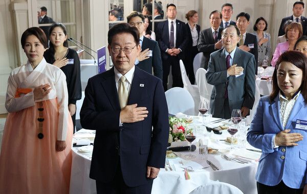 이재명&nbsp;대통령과 김혜경 여사가 9일(현지시간) 벨기에 브뤼셀 한 호텔에서 열린 동포 만찬간담회에서 국기에 경례하고 있다. [사진=연합뉴스]