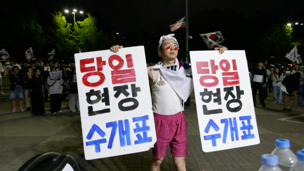 서울 올림픽공원 핸드볼경기장 앞 시위 현장에서 한 시민이 '당일개표 수개표'라고 적은 판넬을 들고 있다. 2026.6.11. [사진=폴리뉴스]