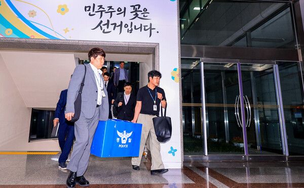 6·3 전국동시지방선거 투표용지 부족 사태를 들여다보고 있는 검경 합동수사본부 관계자들이 11일 경기도 과천 중앙선거관리위원회에서 압수수색을 마친 뒤 압수품을 들고 건물을 나서고 있다. [사진=연합뉴스]