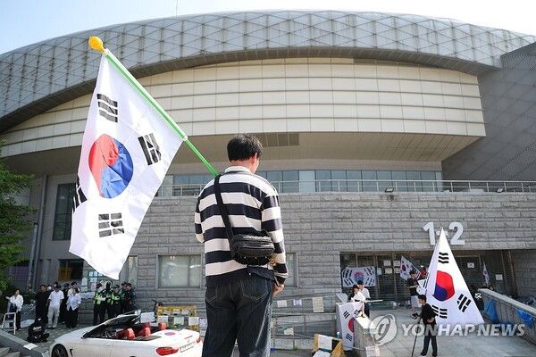 6·3 지방선거 투표용지 부족 사태로 빚어진 '잠실 개표소 봉쇄 시위'가 이어지고 있는 11일 서울 송파구 올림픽공원 핸드볼경기장에서 한 참가자가 태극기를 들고 있다. 2026.6.11 [사진=연합뉴스]